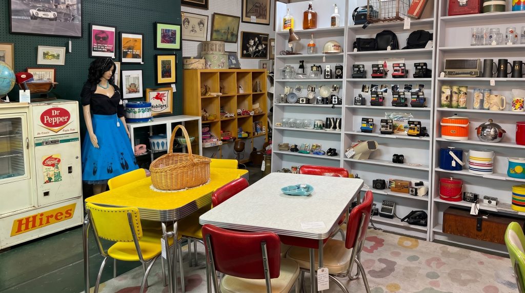 Mid-century modern furniture and vintage collectibles at Antique Harvest Healdsburg, featuring 1950s Formica kitchen tables, retro vinyl chairs, and a collection of vintage Polaroid cameras.